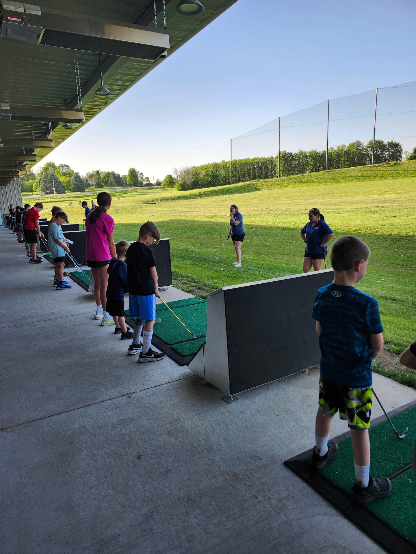 Kids lined up in bays at The Flight Zone during a youth golf activity